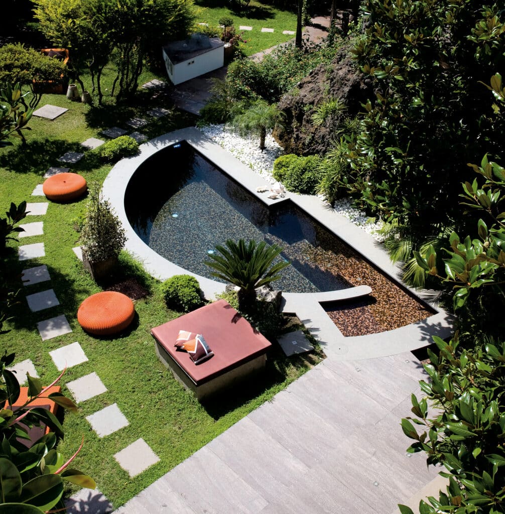 Aménagement de Jardin Moderne avec Petite Piscine Design Piscine moderne incurvée dans un jardin paysager luxuriant avec poufs orange et sentier en dalles de pierre.